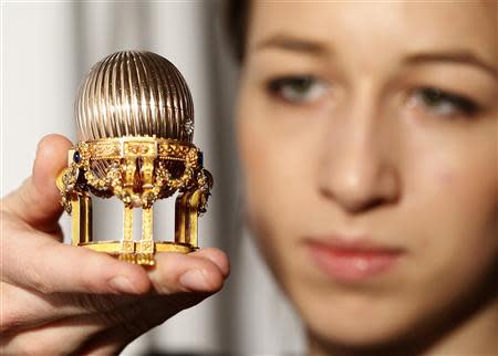 An assistant poses for a photograph with a Faberge egg during a photo-call at antique dealer Wartski, in central London April 7, 2014. REUTERS/Olivia Harris