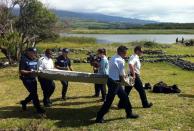 Police on Reunion island carry a wing part from flight MH370, on July 29, 2015