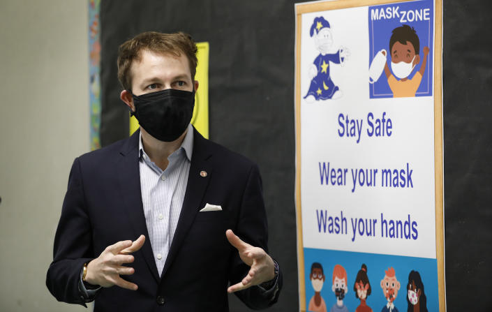 Nick Melvoin stands next to a poster about COVID-19 safety protocols.