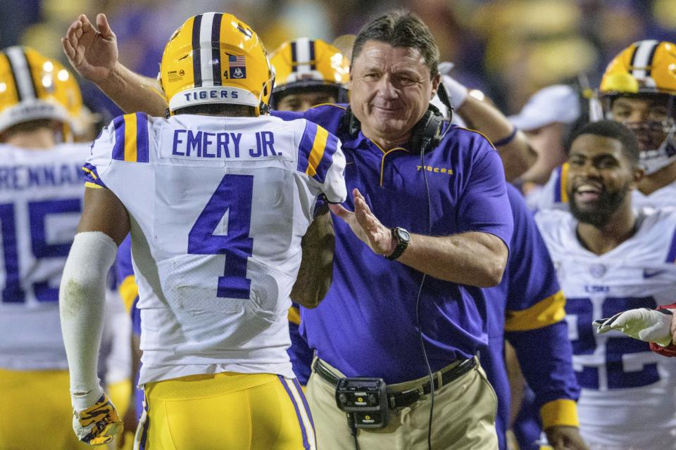 LSU coach Ed Orgeron congratulates running back John Emery Jr. (4), who scored against Arkansas during the second half of an NCAA college football game in Baton Rouge, La., Saturday, Nov. 23, 2019. (AP Photo/Matthew Hinton)