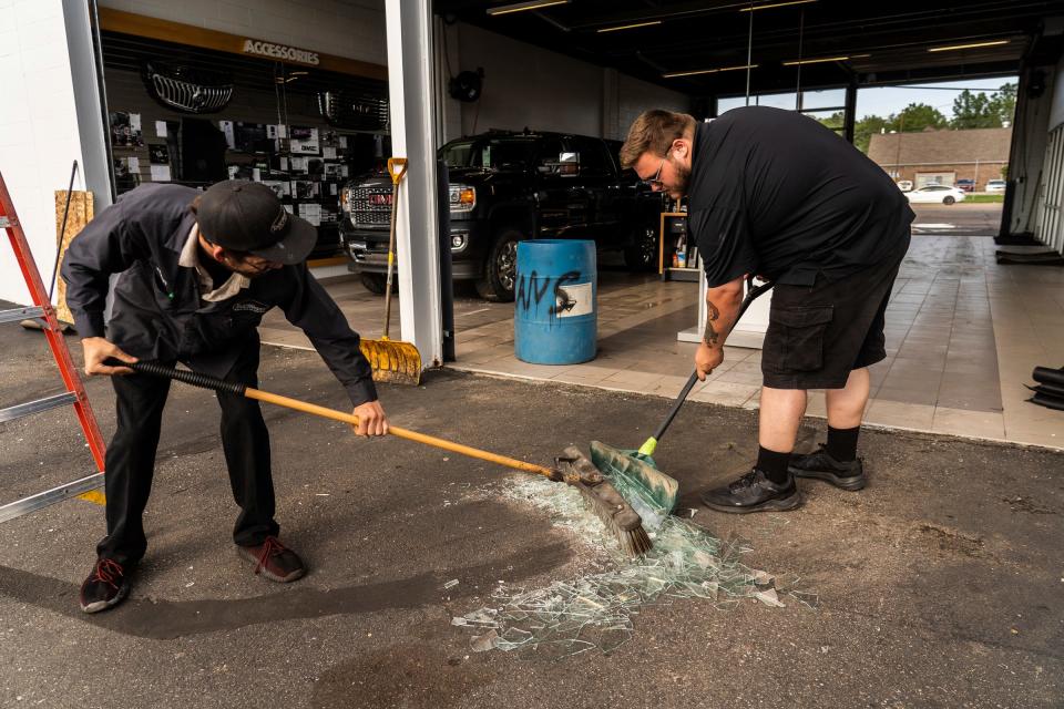 Todd Wenzel Buick GMC Of Davison employees sweep glass from broken bay windows damaged by baseball-sized hail that came through Davison during a storm that moved through Michigan on Thursday, July 20, 2023.