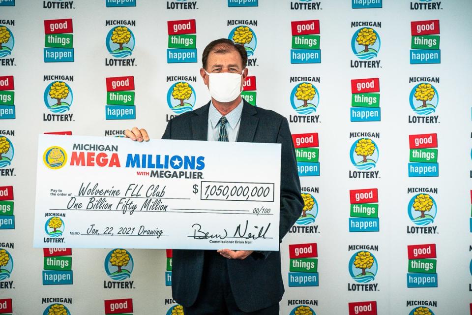 Attorney Kurt Panouses poses with a check on behalf of the winners of a Mega Millions lottery jackpot. Source: Michigan Lottery via AP