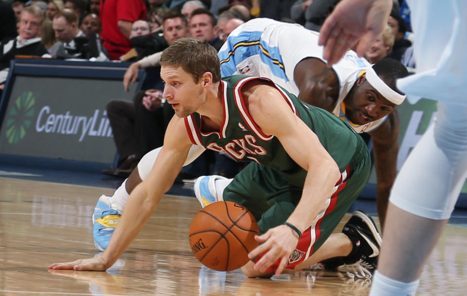 Milwaukee Bucks guard Luke Ridnour, front, picks up loose ball as Denver Nuggets guard Ty Lawson covers in the first quarter of an NBA basketball game in Denver, Wednesday, Feb. 5, 2014. (AP Photo/David Zalubowski)