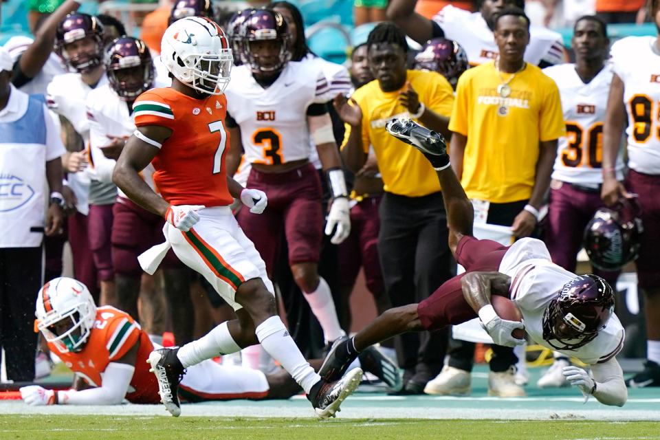 Bethune Cookman's Marcus Riley, right, gets past Miami safety Kamren Kinchens (24) and cornerback Al Blades Jr. (7) for a first down during the first half of an NCAA college football game, Saturday, Sept. 3, 2022, in Miami Gardens, Fla. (AP Photo/Lynne Sladky)