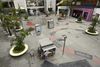 A vendor waits for customers in a sparsely populated courtyard at the Hollywood & Highland shopping and entertainment complex, Thursday, March 12, 2020, in the Hollywood section of Los Angeles. (AP Photo/Chris Pizzello)