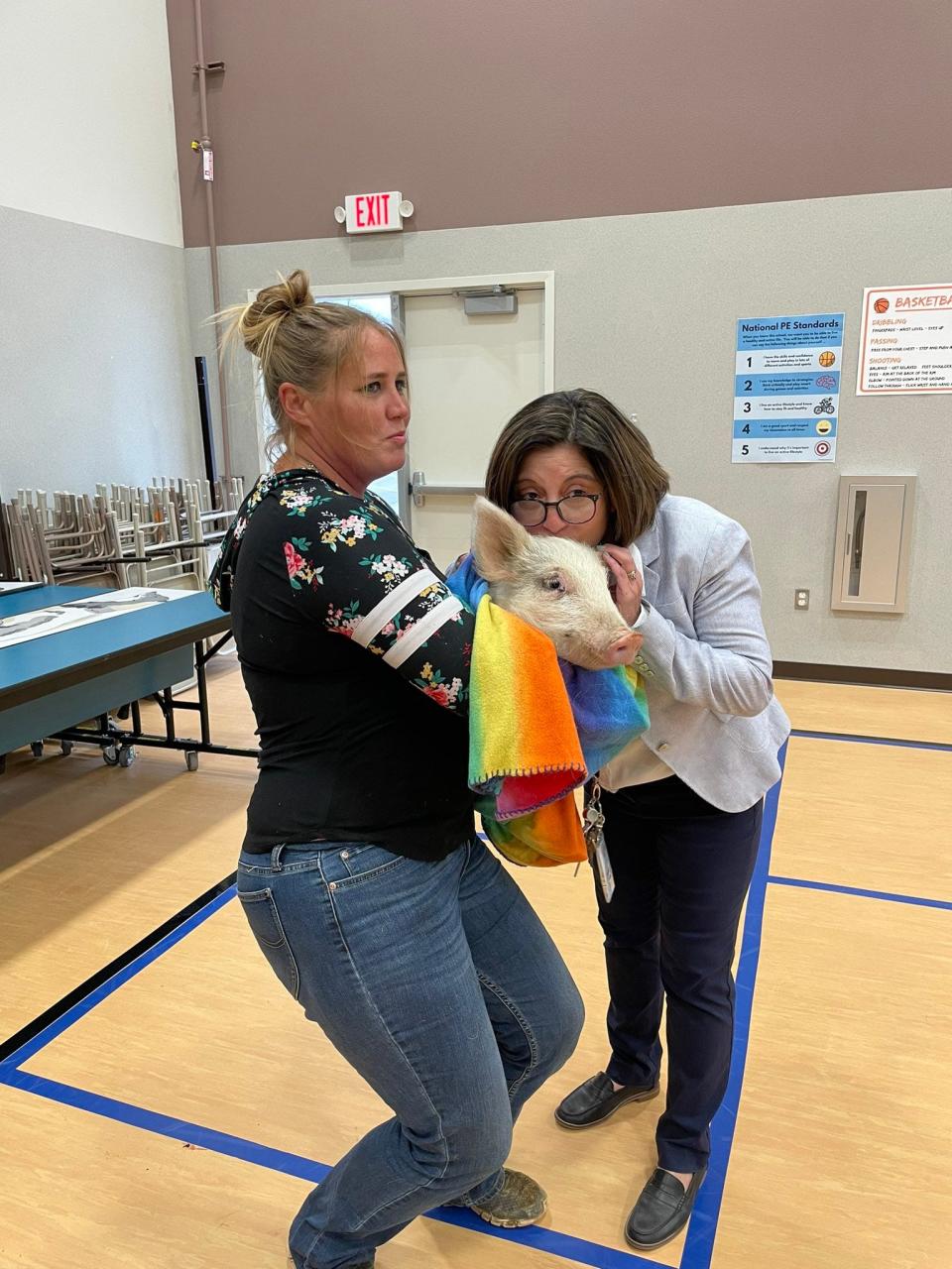 Haven Meredith of Enchanted Valley Rescue holds a pig for Sunset Hills Elementary School Principal Catherine Diaz to kiss at an assembly December 10, 2021.

Diaz held a contest that if the Sunset Hills student body read 10,000 books then she would kiss a pig.