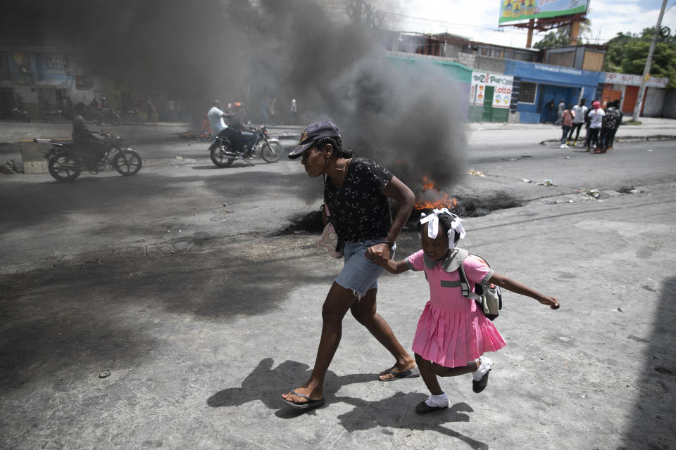 FILE - A woman guides a child past a demonstration against increasing violence in Port-au-Prince, Haiti, Tuesday, March 29, 2022. The protest coincides with the 35th anniversary of Haiti's 1987 constitution and follows other protests and strikes in recent weeks in the middle of a spike in gang-related kidnappings. (AP Photo/Odelyn Joseph, File)