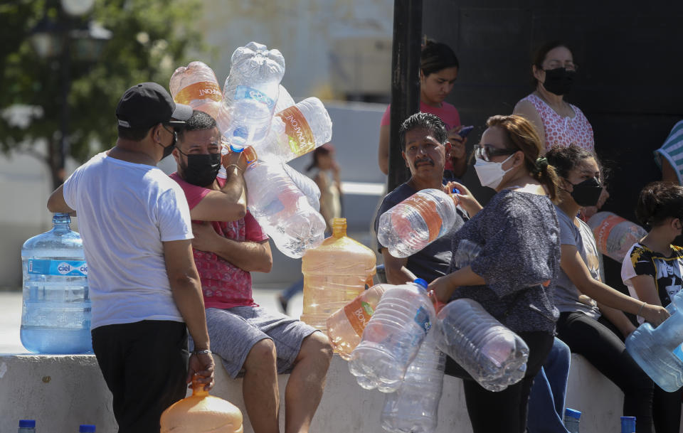 Neighbors wait with plastic containers in hand to collect water at a public collection point in Monterrey, Mexico, Monday, June 20, 2022. Local authorities began restricting water supplies in March, as a combination of an intense drought, poor planning and high use has left the three dams that help supply the city dried up, with thousands of homes not receiving any water for weeks. (AP Photo)