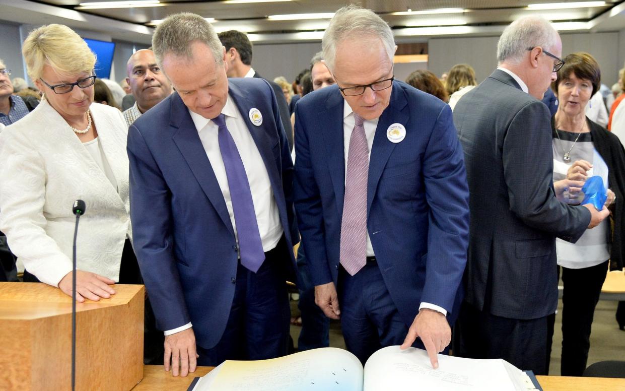 Opposition Leader Bill Shorten and Australian Prime Minister Malcolm Turnbull (right) look through the Message to Australia book that was published from hand-written letters from victims of child sexual abuse  - AFP
