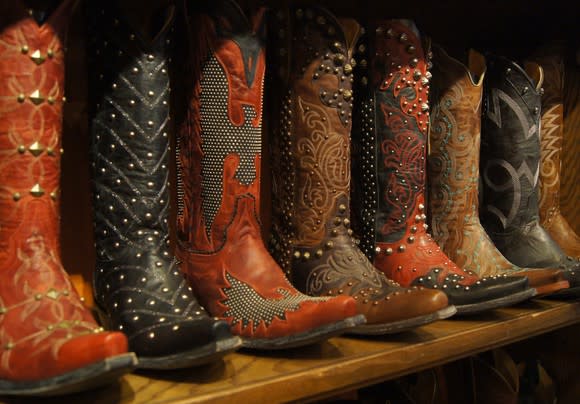 Ornate cowboy boots lined up on a wooden shelf