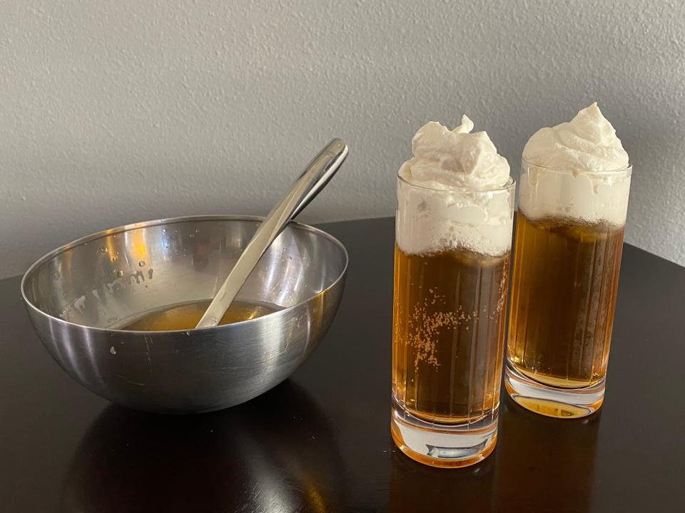 glasses of butterbeer next to a metal mixing bowl on a kitchen table