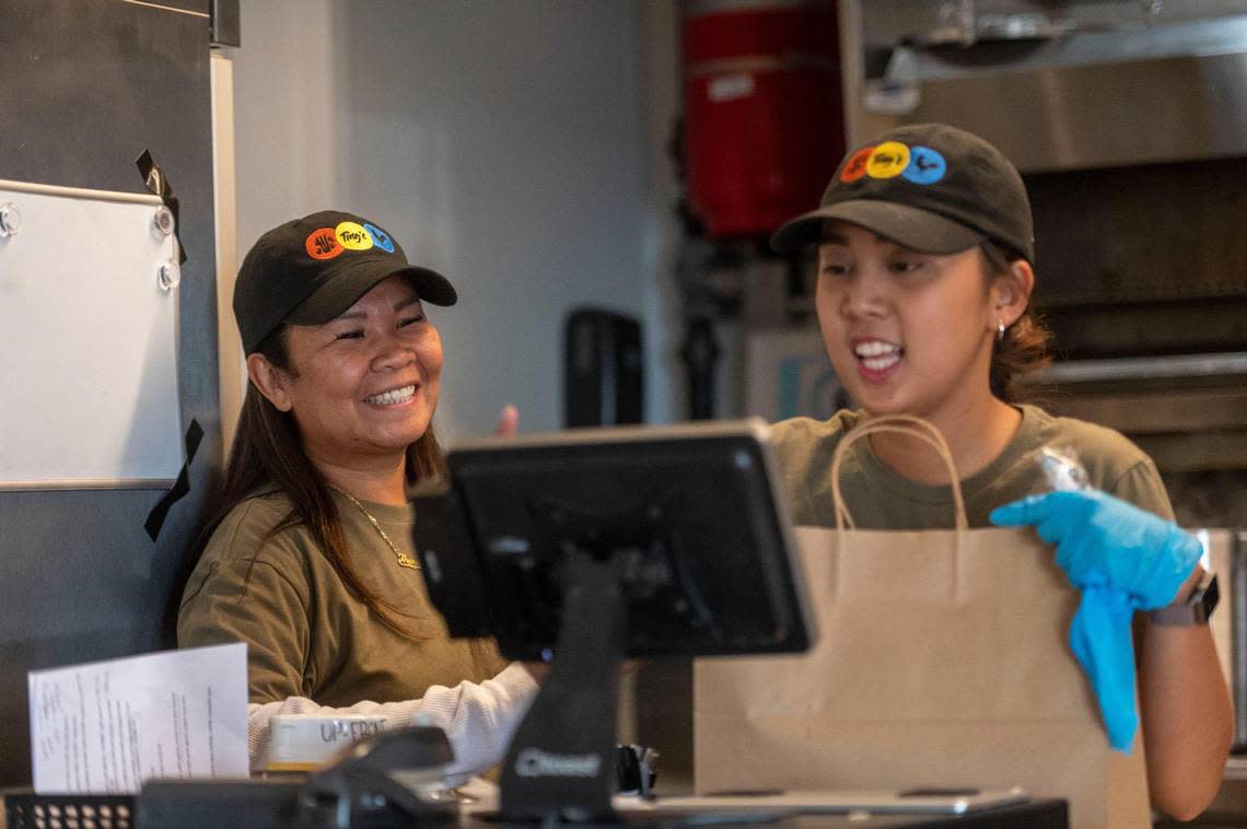 Theresa “Ting” Santos, owner of Ting’s Filipino Bistro, left, teaches Alex Mercene how to use a new register system during the grand opening at Parlor earlier this year.