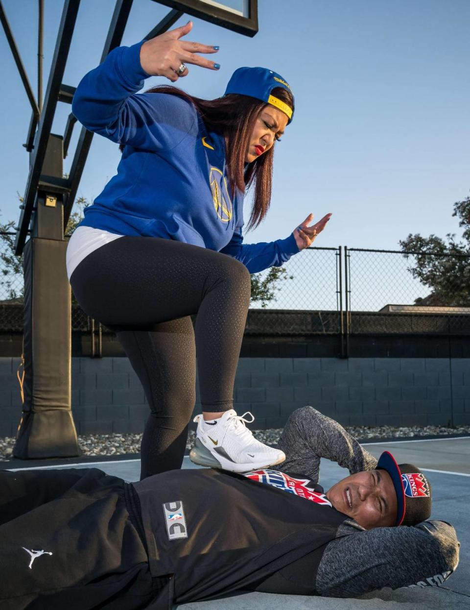 Golden State Warriors fan Carmel Sangco and her husband, Sacramento Kings fan Robert Sangco, are on opposite sides of NBA playoff matchup. They playfully recreate a scene from Game 2 of the series while on their backyard court Wednesday in Elk Grove.