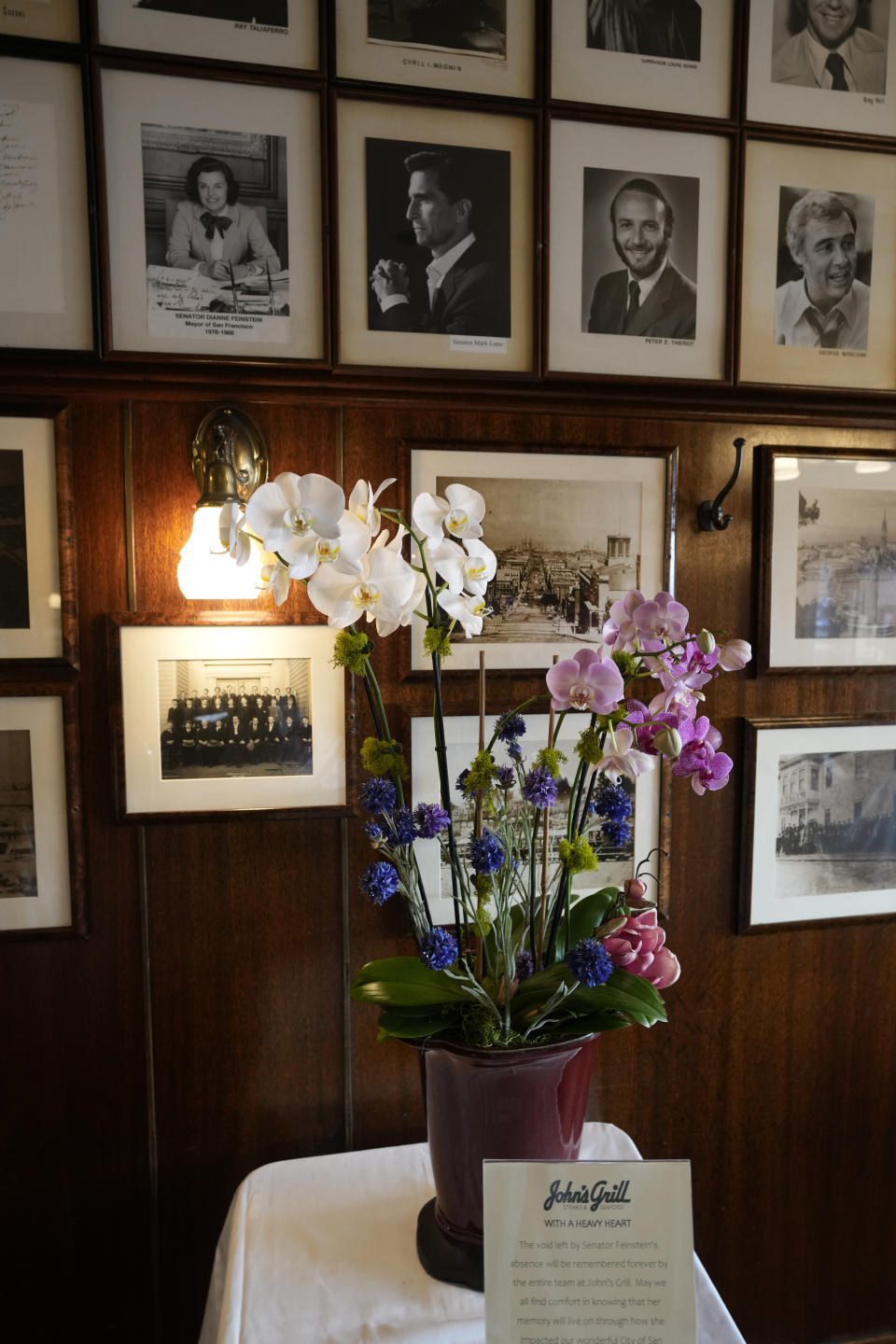 Flowers for the late Sen. Dianne Feinstein are seen below her photo hanging at John's Grill in San Francisco, Wednesday, Oct. 4, 2023. The restaurant, which celebrated its 115th anniversary Wednesday with a free lunch and appearances by San Francisco Mayor London Breed and other politicians, paid tribute to Sen. Feinstein who died last week. (AP Photo/Eric Risberg)