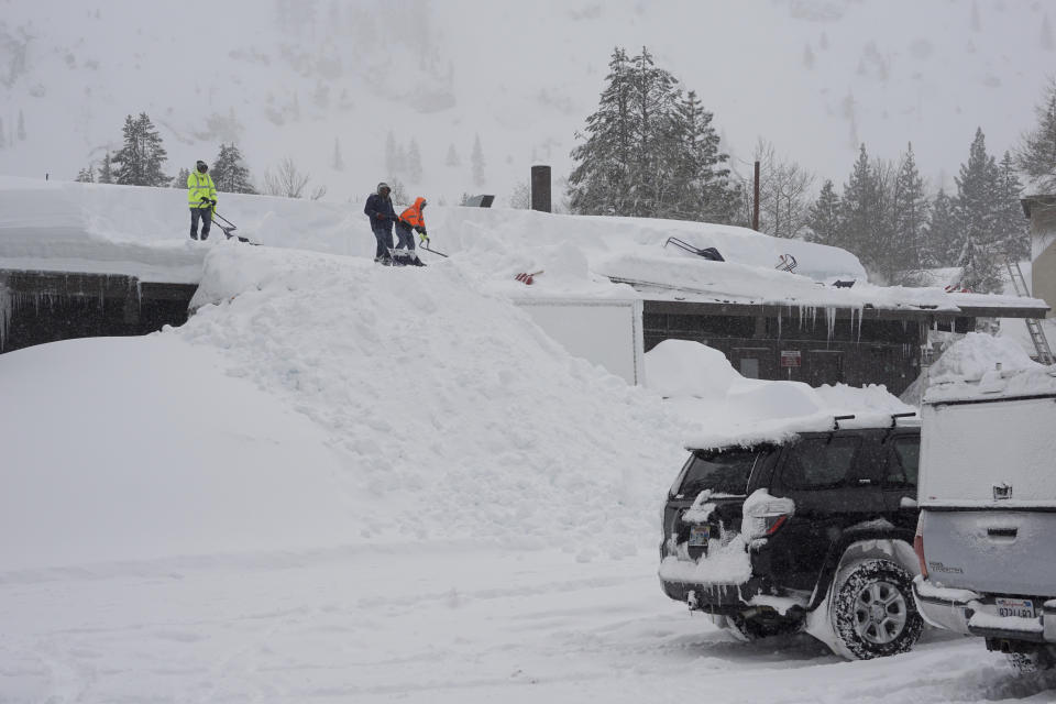 Workers clear snow off the roof of a building during a blizzard Sunday, March 3, 2024, in Olympic Valley, Calif. (AP Photo/Brooke Hess-Homeier)