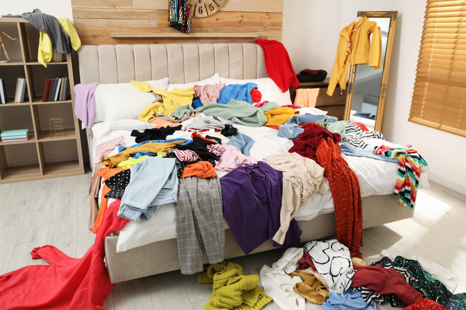 Pile of clothes on bed in messy room