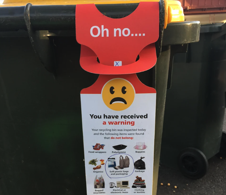 a red warning tag on a recycling bin.