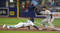 Tampa Bay Rays' Randy Arozarena, left, dives back to first ahead of the pickoff throw to San Francisco Giants first baseman LaMonte Wade Jr. during the first inning of a baseball game Friday, April 12, 2024, in St. Petersburg, Fla. (AP Photo/Chris O'Meara)