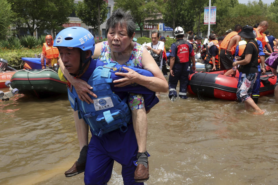 Rescuers evacuate people from a flooded area in Weihui in central China's Henan Province, Monday, July 26, 2021. Residents laid flowers on Tuesday at the entrance of a subway station where more than a dozen people died after a record-breaking downpour flooded large swaths of Henan province in central China. (Chinatopix via AP)