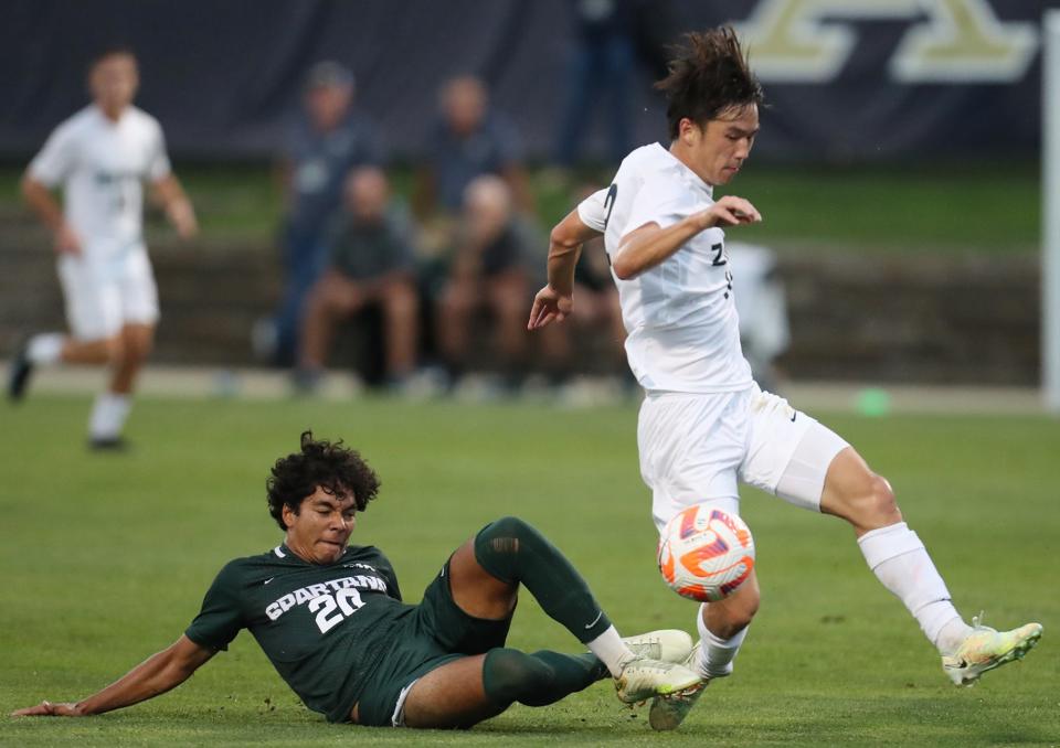 Michigan State University's Tyler Crawford takes out the foot of University of Akron's Gyuwon Chong in the first half of their men's soccer match in Akron on Monday. The Zips beat the Spartans 2-1.