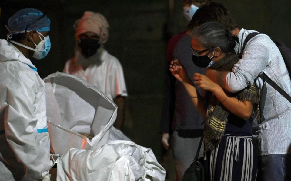 Relatives grieve for the loss of a loved one, at a crematorium in New Delhi - ARUN SANKAR/AFP