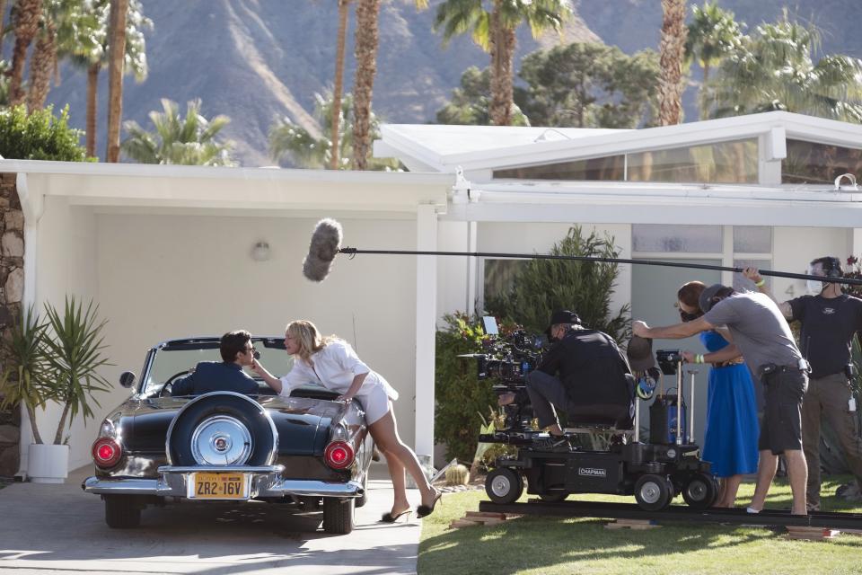 DON’T WORRY DARLING, Harry Styles (left), Florence Pugh (center of frame), director Olivia Wilde (blue dress), on set, 2022. ph: Merrick Morton /© Warner Bros. / Courtesy Everett Collection