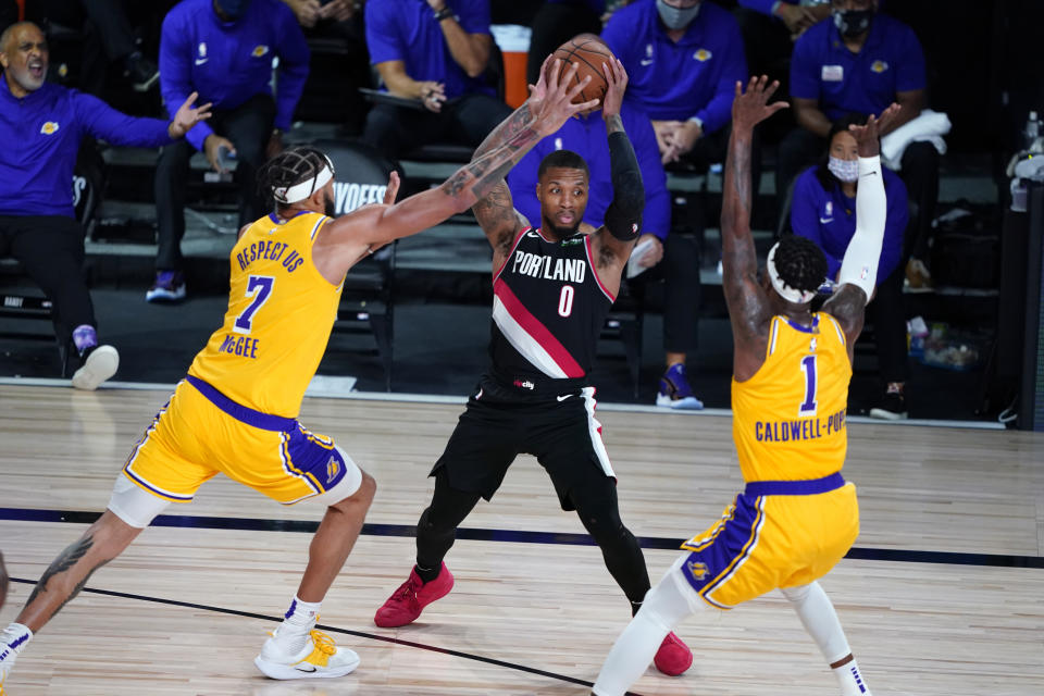 Portland Trail Blazers guard Damian Lillard (0) tries to pass under pressure from Los Angeles Lakers center JaVale McGee (7) and guard Kentavious Caldwell-Pope (1) during the second half of an NBA basketball game Tuesday, Aug. 18, 2020, in Lake Buena Vista, Fla. (AP Photo/Ashley Landis, Pool)