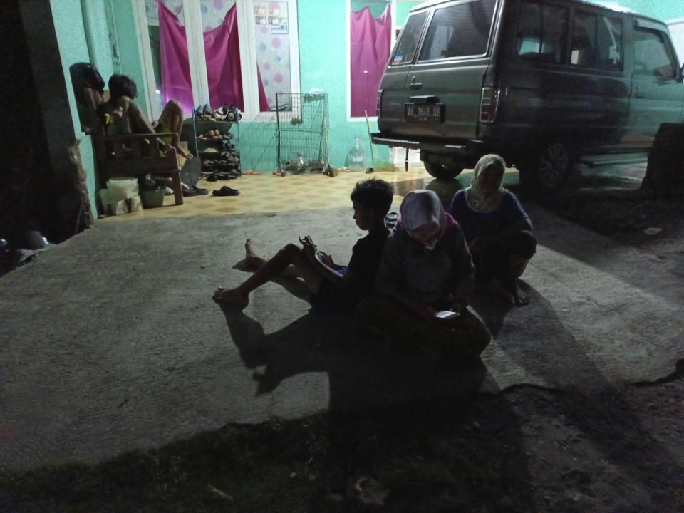 People wait outside their homes following an earthquake in Bantul district, outside Yogyakarta, Indonesia, Friday, June 30, 2023. A strong earthquake shook parts of Indonesia's main island of Java on Friday, causing panic but no immediate reports of serious damage or casualties.(AP Photo/Mahmud)