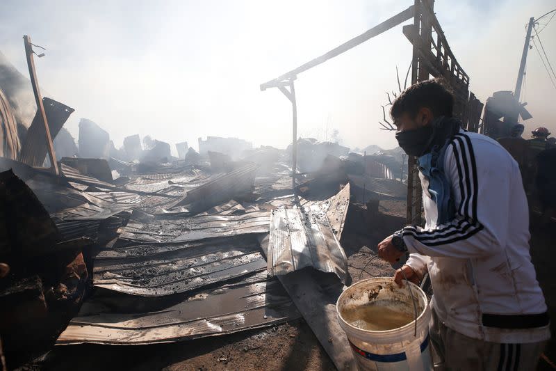 A man carries a bucket full of water as helps to extinguish a fire in Valparaiso