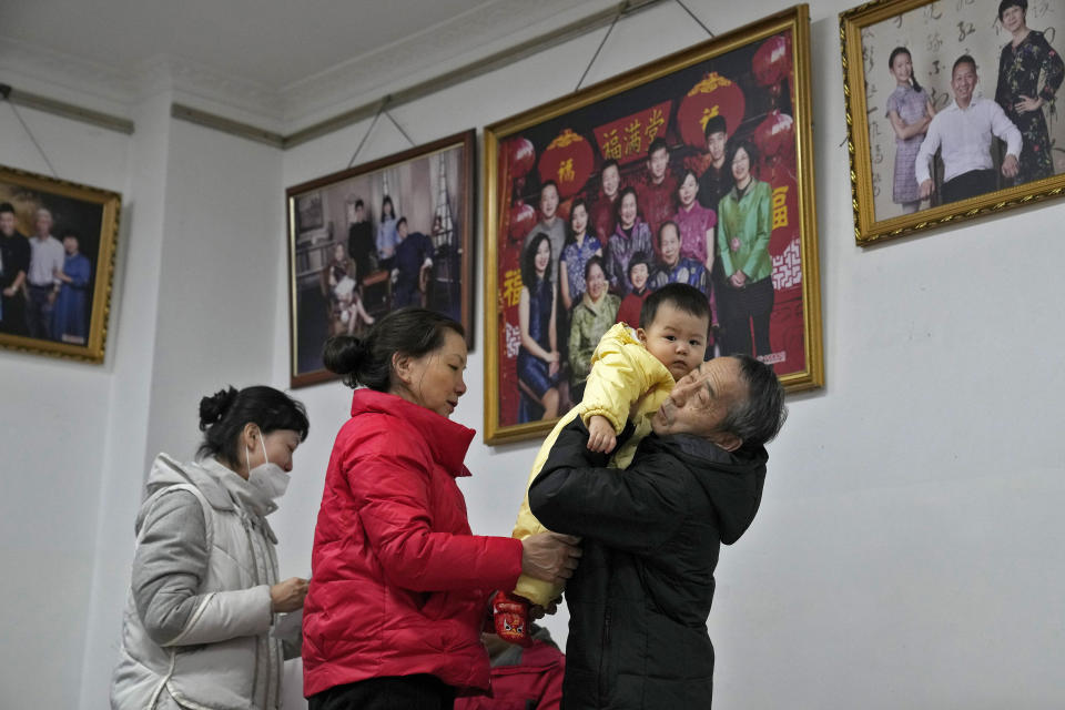 A man carries his grandchild preparing to leave after taking a family photo with his family members at a photo studio in Beijing, Tuesday, Jan. 17, 2023. For the first time in decades, China has fewer people than it did at the start of last year, according to official figures released Tuesday. The world's most populous country has worried for years about an aging population's effect on the economy and society, but the population was not expected to go into decline for almost a decade. (AP Photo/Andy Wong)