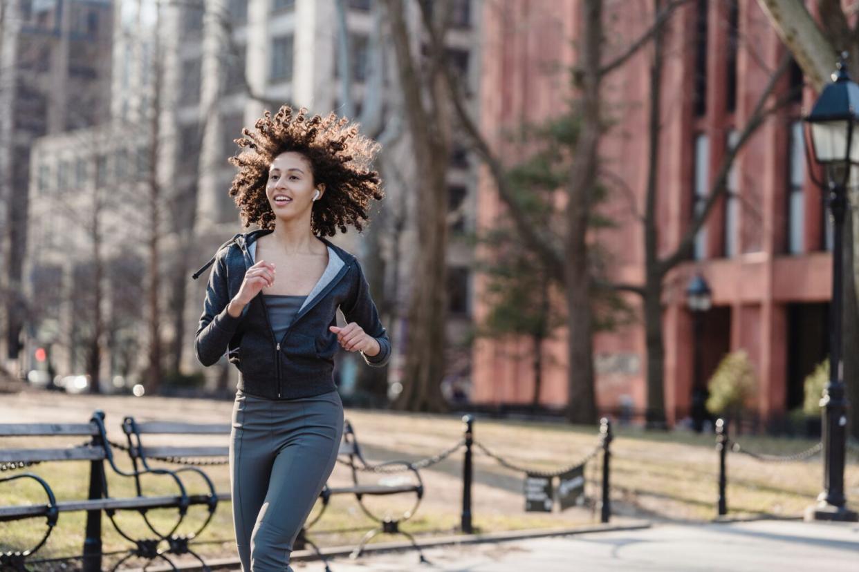 woman running in the park with a zip up hoodie and leggings on