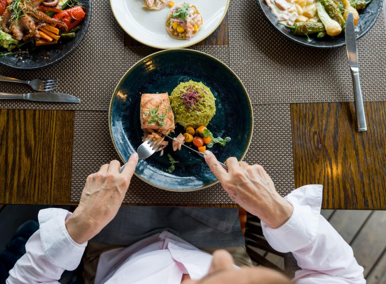 Close-up on a woman eating salmon for dinner at a restaurant - food and drink concepts