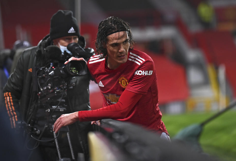 Manchester United's Edinson Cavani gets up after running into the advertising boards during the English Premier League soccer match between Manchester Utd and Wolverhampton Wanderers at Old Trafford stadium in Manchester, England, Tuesday,Dec. 29, 2020. (Laurence Griffiths, Pool via AP)