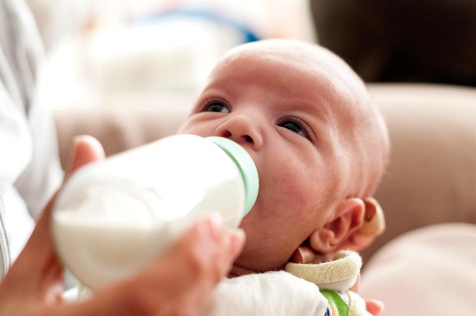 Baby boy drinking milk at feeding bottle