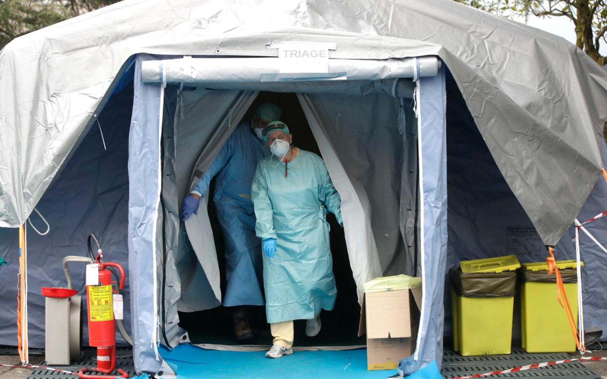 Medical staff walk out of a tent at one of the emergency structures that were set up to ease procedures at the Brescia hospital, northern Italy - Luca Bruno/AP