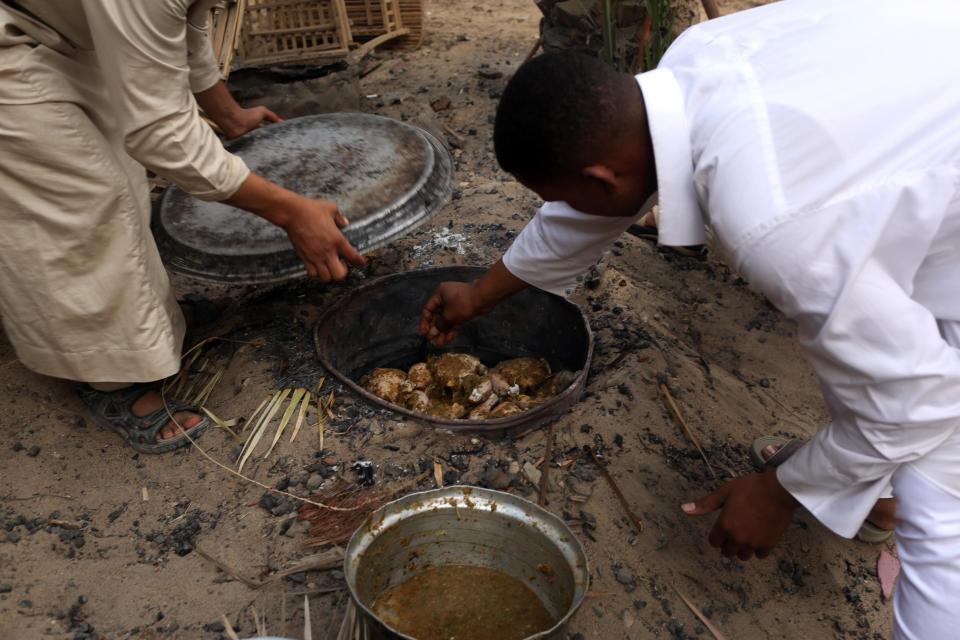 Workers of a small hotel cook chicken in a traditional way called 'abu mardam' in Siwa