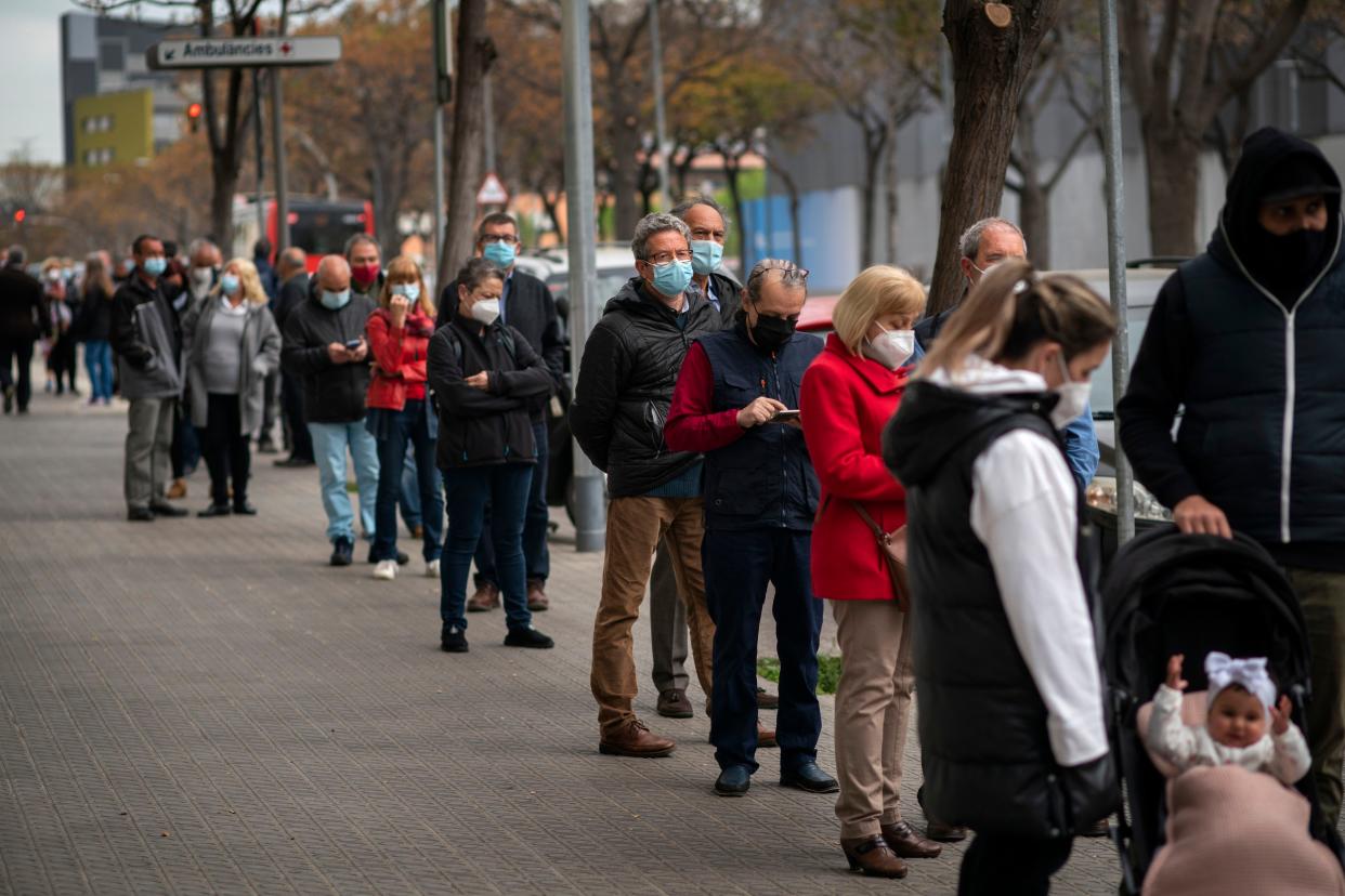 People line up outside a public ambulatory as they wait to receive a dose of the AstraZeneca vaccine in Barcelona, Spain, Tuesday, April 6, 2021. Spanish Prime Minister Pedro Sánchez says a steep rise in vaccine deliveries over the coming months will allow the country to inoculate 70% of its adult population against COVID-19 by the end of August. That's some 33 million people. He said Tuesday that Spain expects to receive 87 million doses by September.