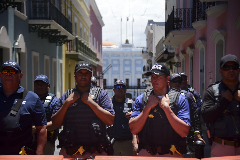 Police stand guard around the La Fortaleza residence of Gov. Ricardo Rosselló where people gather to protest against Rosselló in San Juan, Puerto Rico, Wednesday, July 17, 2019. Protesters are demanding Rosselló step down for his involvement in a private chat in which he used profanities to describe an ex-New York City councilwoman and a federal control board overseeing the island's finance. (AP Photo/Carlos Giusti)