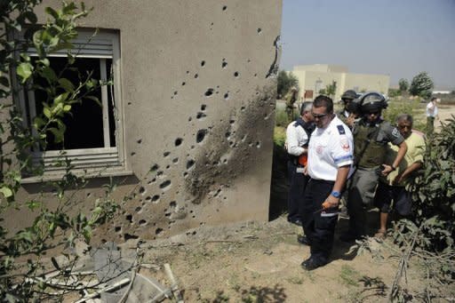 An Israeli paramedic and border police survey the damage caused by a rocket launched from the Gaza Strip and which hit the Saad Kibbutz in southern Israel. The military wing of Hamas said late on Wednesday it had agreed to an Egyptian-brokered ceasefire with Israel, after three days of bloodshed in and around Gaza