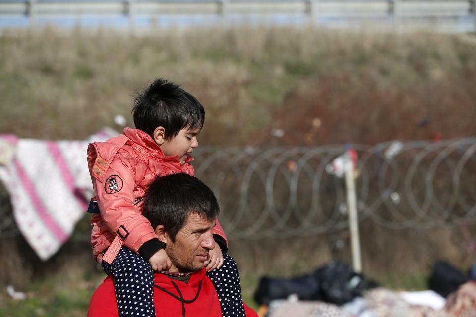 Un hombre carga a su hijo sobre sus hombros, en un campo donde acampan varios migrantes en Edirne, cerca de la frontera turca con Grecia, el domingo 8 de marzo de 2020. (AP Foto/Darko Bandic)