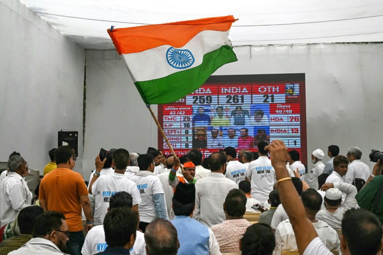 A supporter of the Indian National Congress (INC) party waves the national flag as others watch results during vote counting in New Delhi (Arun SANKAR)