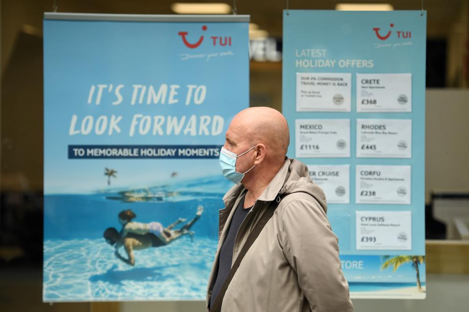 A man wearing a face mask or covering due to the COVID-19 pandemic, walks past the window of a TUI travel agent&#39;s holiday shop in Liverpool, north west England on October 2, 2020, following the  announcement of new local restrictions for certain areas in the northwest of the country, due to a resurgence of novel coronavirus cases. - The British government on Thursday extended lockdowns to Liverpool and several other towns in northern England, effectively putting more than a quarter of the country under tighter coronavirus restrictions. Health Secretary Matt Hancock said limits on social gatherings would be extended to the Liverpool City region, which has a population of about 1.5 million. (Photo by Oli SCARFF / AFP) (Photo by OLI SCARFF/AFP via Getty Images)