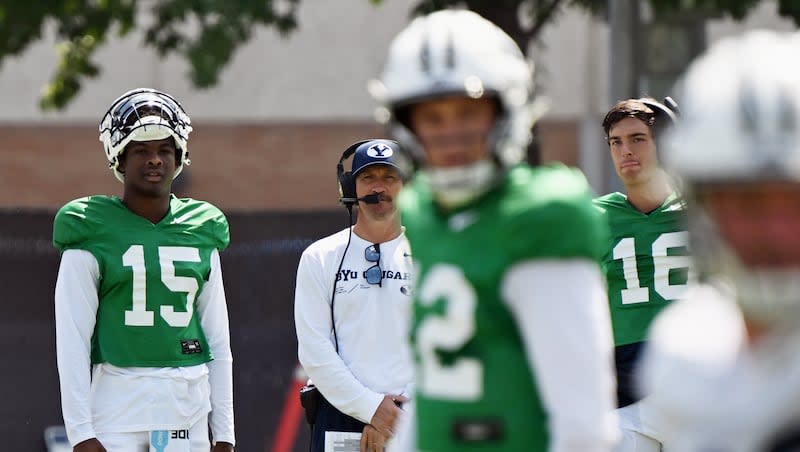 BYU Cougars quarterbacks coach Aaron Roderick watches from he sidelines with Nick Billoups (15) and Cole Hagen (16) as Jake Retzlaff works with the offense as BYU’s football team practices in Provo on Tuesday, Aug. 8, 2023. Retzlaff and transfer Gerry Bohanon have the inside track to be QB1 next fall, but there are two prized high school QBs that are on the Cougars' radar down the road.
