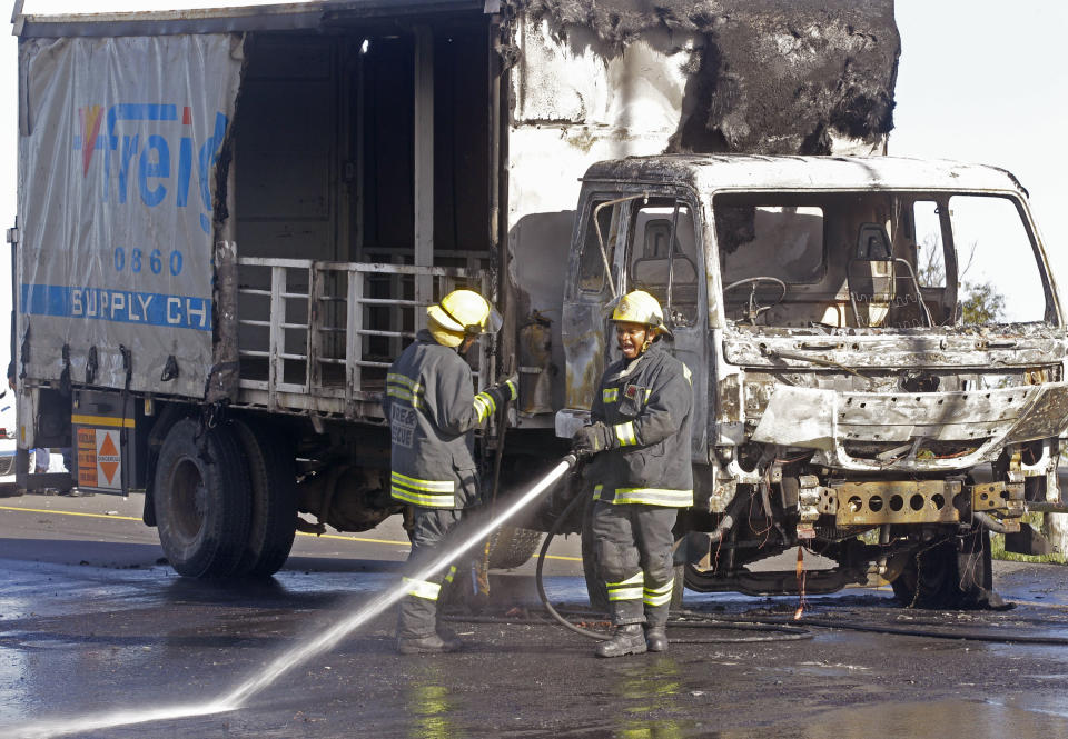 A fireman spray fuel off the road after a truck was set alight by striking truck workers on a slipway off a main highway leading out of the city, near the international airport in Cape Town, South Africa, Friday, Oct 5, 2012. South African truck workers are on strike over wages for the past two weeks with sporadic violence reported and a number of trucks being set alight in past days. (AP Photo/Schalk van Zuydam)