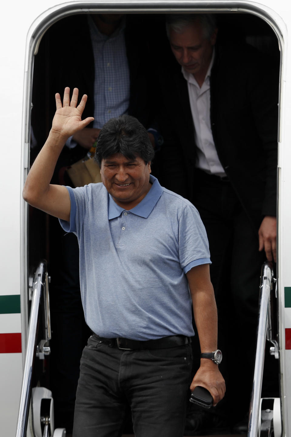 Former Bolivian President Evo Morales waves upon arrival in Mexico City, Tuesday, Nov. 12, 2019. Mexico granted asylum to Morales, who resigned on Nov. 10 under mounting pressure from the military and the public after his re-election victory triggered weeks of fraud allegations and deadly protests. (AP Photo/Eduardo Verdugo)