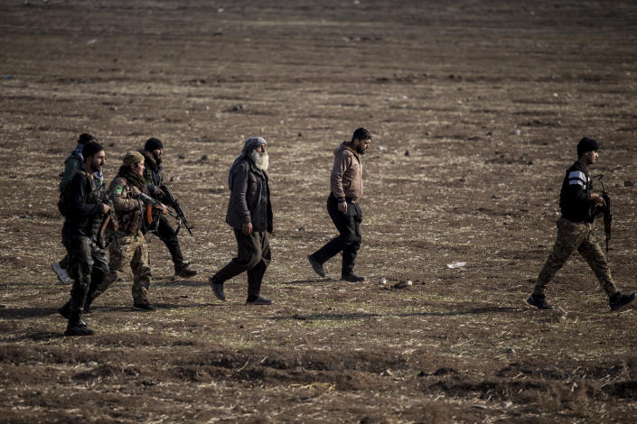 Syrian Democratic Forces fighters escort suspected Islamic State militants in Hassakeh, northeast Syria, Wednesday, Jan. 26, 2022. Dozens of armed Islamic State militants remained holed up in the last occupied section of a Syrian prison, U.S.-backed Kurdish-led forces said Thursday. The two sides clashed a day after the Syrian Democratic Forces announced they had regained full control of the facility. (AP Photo/Baderkhan Ahmad)