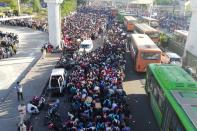 Migrant workers and their family members lineup outsdie the Anand Vihar bus terminal to leave for their villages during a government-imposed nationwide lockdown as a preventive measure against the COVID-19 coronavirus in New Delhi on March 28, 2020. - Tens of thousands of migrant workers and their famiies on March 28 fought and shoved their way onto buses organised by India's most populous state to get them to their home towns amid the coronavirus pandemic. (Photo by Bhuvan BAGGA / AFP) (Photo by BHUVAN BAGGA/AFP via Getty Images)