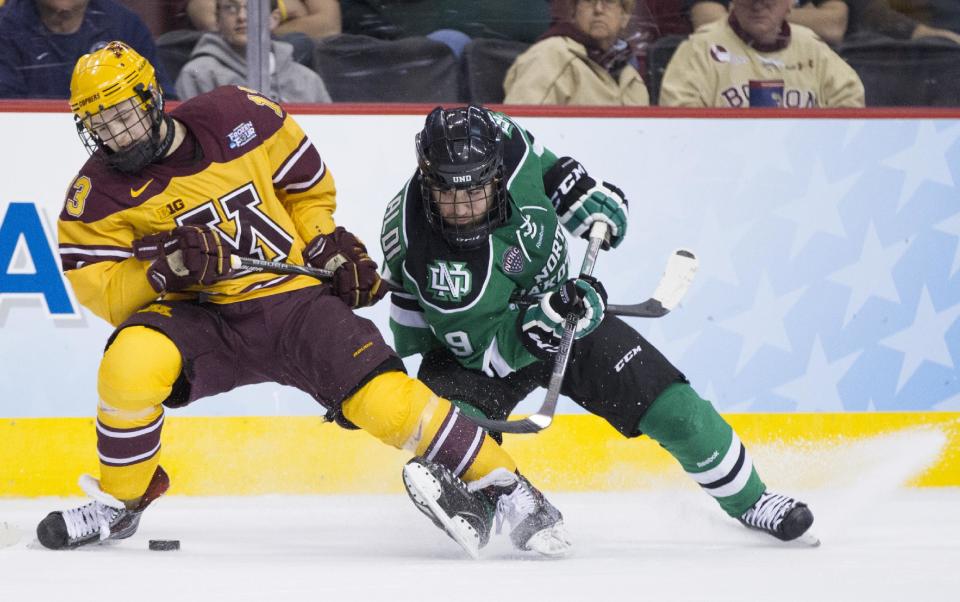 Minnesota's Taylor Cammarata, left, battles with North Dakota's Rocco Grimaldi, right, for the puck during the second period of an NCAA men's college hockey Frozen Four tournament game on Thursday, April 10, 2014, in Philadelphia. (AP Photo/Chris Szagola)