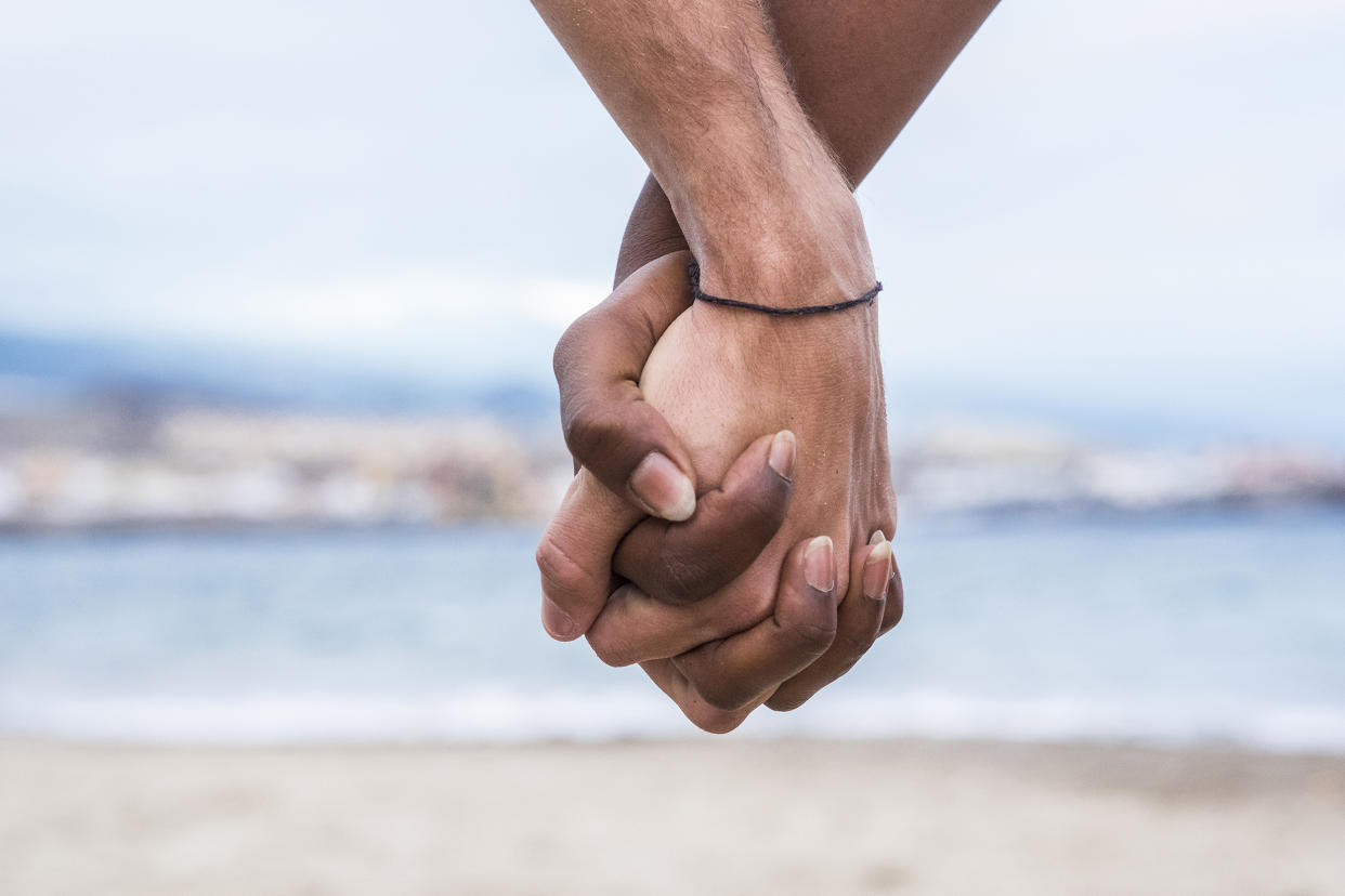 Close-up of two hands connected on the beach (Westend61 / Getty Images stock)