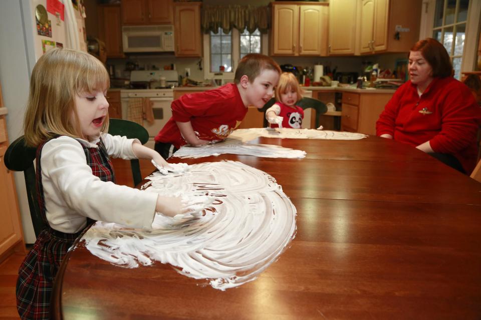 Joanne Kehoe, right, watches while her children, from left, Maria, Anthony and Veronica play with shaving cream on the kitchen table while trying to combat cabin fever, Monday, Feb. 3, 2014, in Indianapolis. (AP Photo/R Brent Smith)